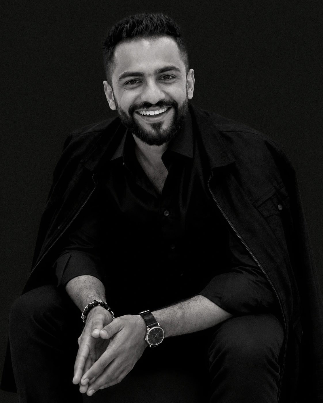 Mohamed Rabie seated and smiling, in an editorial black-and-white portrait